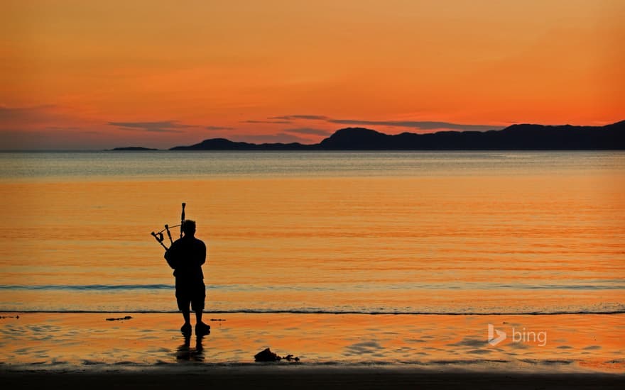 A bagpiper on Arisaig beach in Scotland