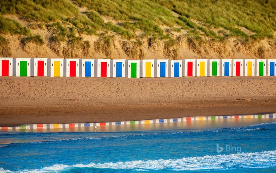 Beach huts reflecting in the water at Woolacombe Beach, Devon